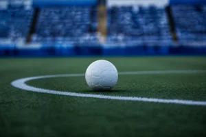 Un balón blanco sobre la línea del círculo central, con las gradas vacías y azules al fondo.